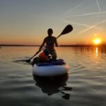Mama und Kleinkind auf dem Stand Up Paddleboard beim Sonnenuntergang
